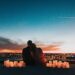 Ein Paar umarmt sich an einem romantischen Ort mit Kerzenlicht und blickt gemeinsam auf eine Stadt bei Sonnenuntergang, um ihre Papierhochzeit zu feiern